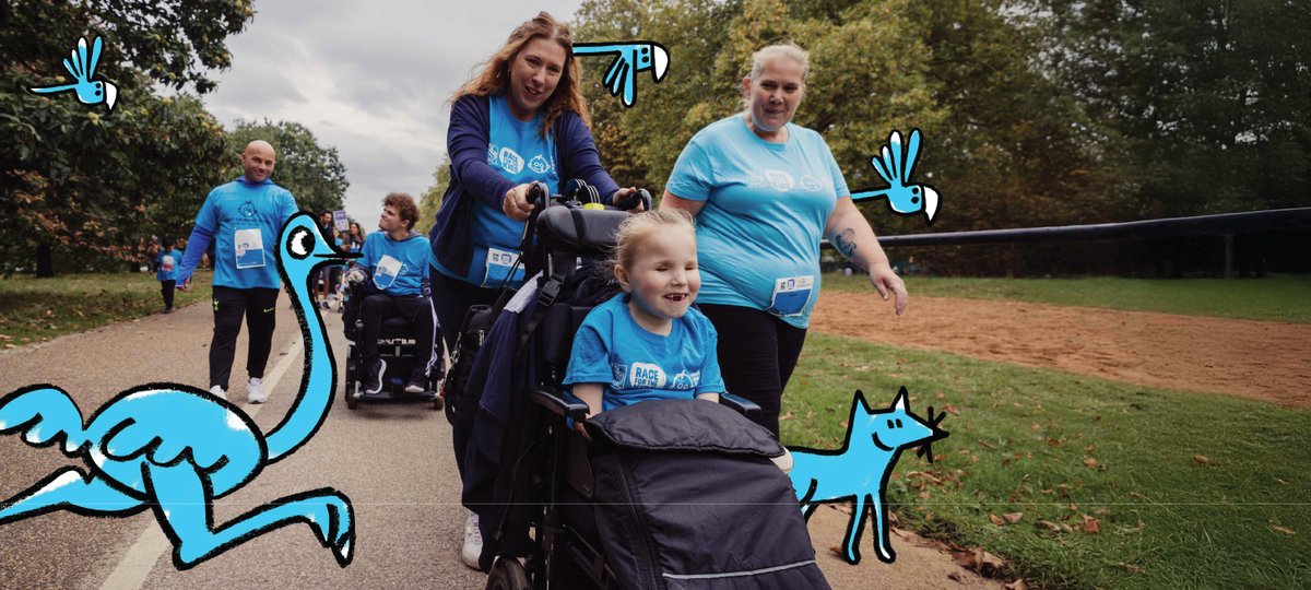 A girl smiles as a family member pushes her wheelchair in an open green space. It is autumn.