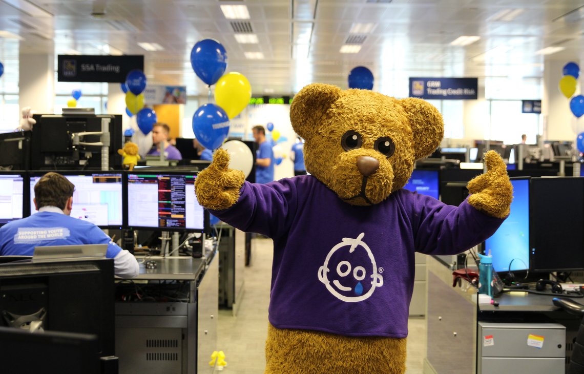 Bernard Bear standing in front of computers in an office