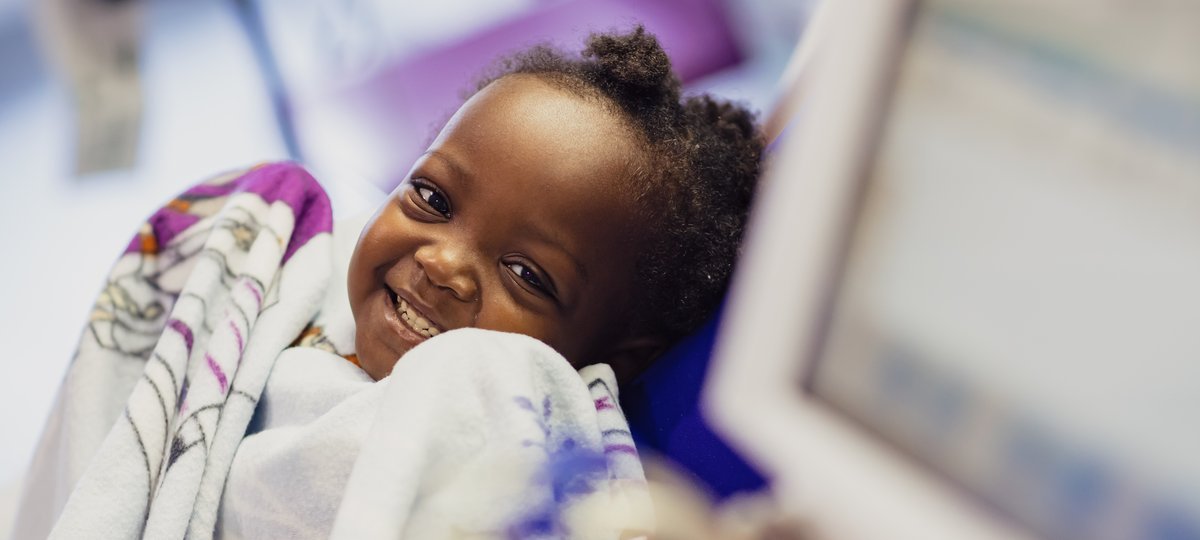 Little girl holding blanket and smiling to camera