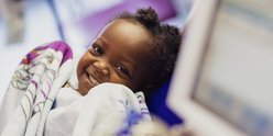 Little girl holding blanket and smiling to camera