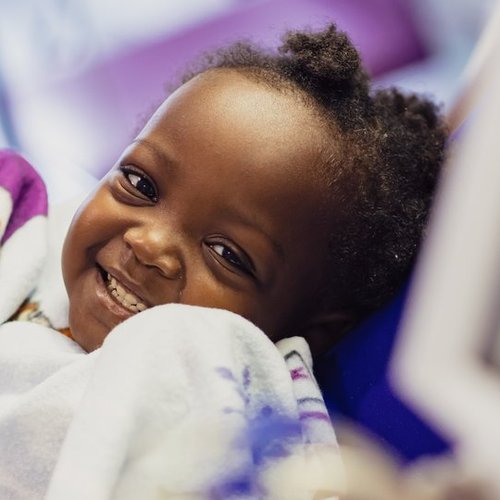 Little girl holding blanket and smiling to camera