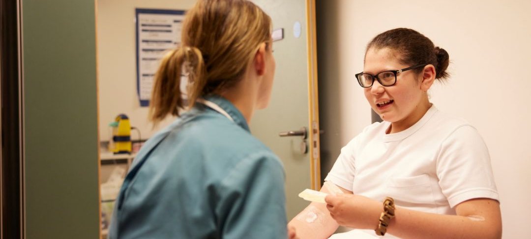 nurse sits with teenage girl in hospital room