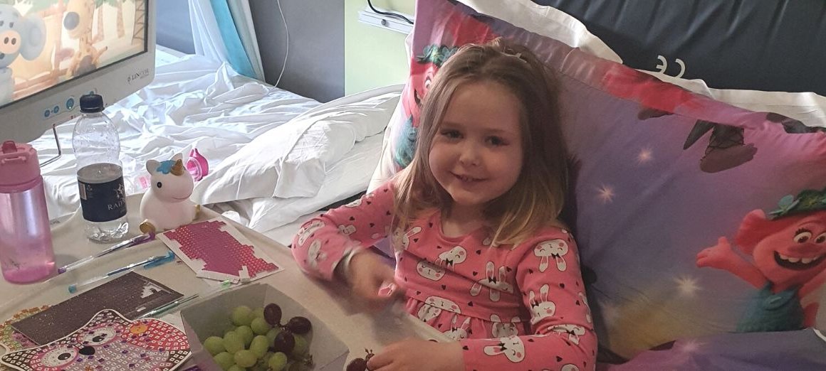 Ellie in her bed at GOSH, smiling to camera