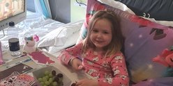 Ellie in her bed at GOSH, smiling to camera