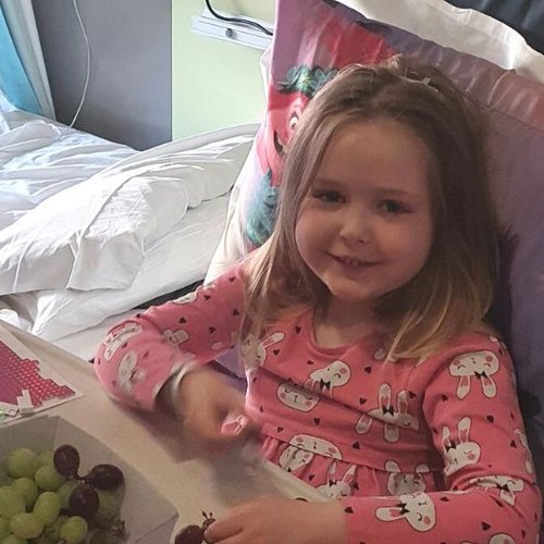 Ellie in her bed at GOSH, smiling to camera