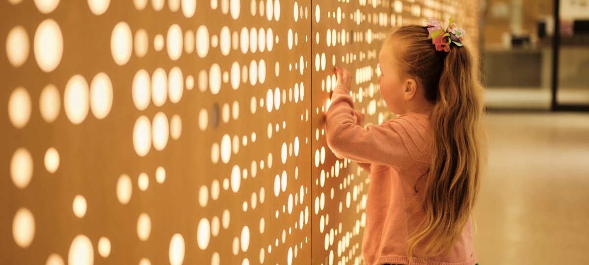 Young girl standing in front of lit-up wall