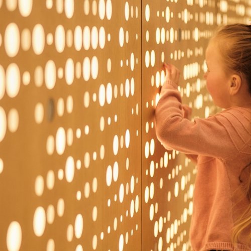 Young girl standing in front of lit-up wall