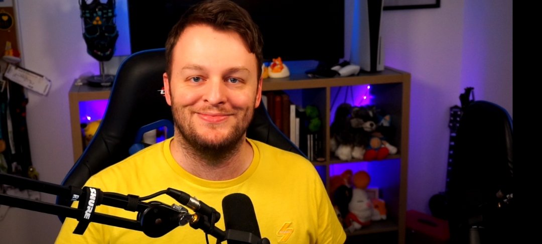 Man sits in front of microphone, smiling to camera
