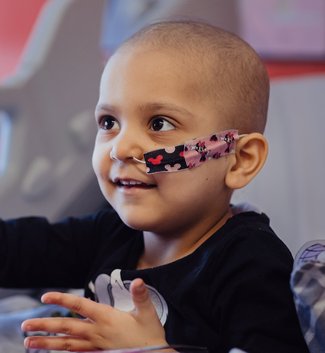 Little girl with feeding tube smiles and looks at person opposite her