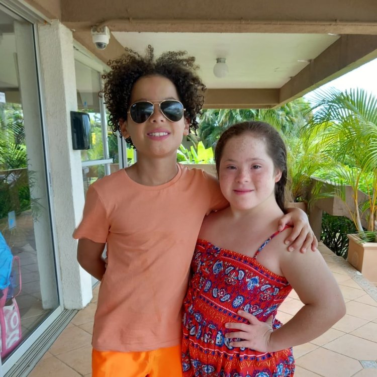 Grace and Max standing next to each other outside on a summer's day, smiling.