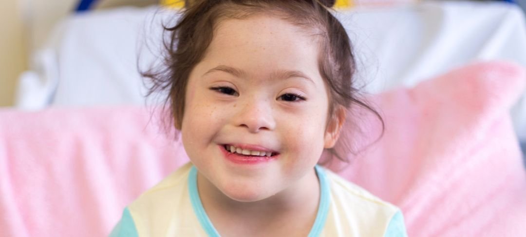 Headshot of a young girl sitting on a bed at GOSH and smiling to camera