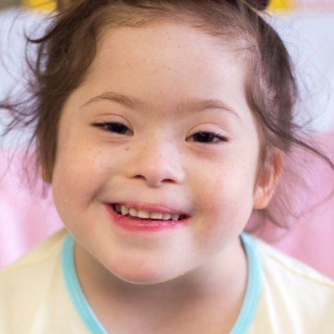 Headshot of a young girl sitting on a bed at GOSH and smiling to camera