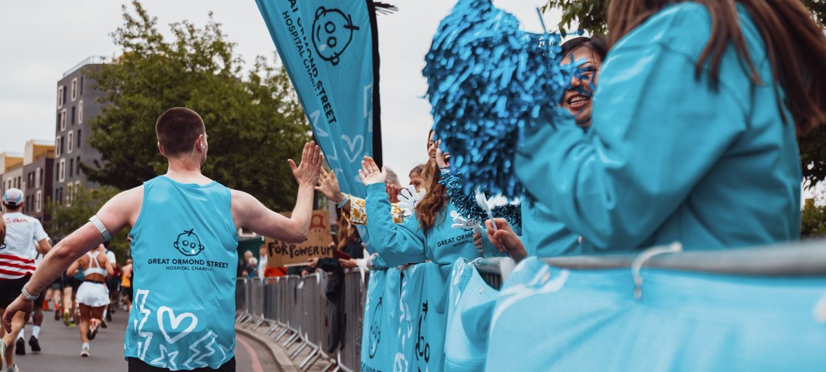 TeamGOSH runner high-fiving volunteers at the GOSH Charity cheer station, as they run past.