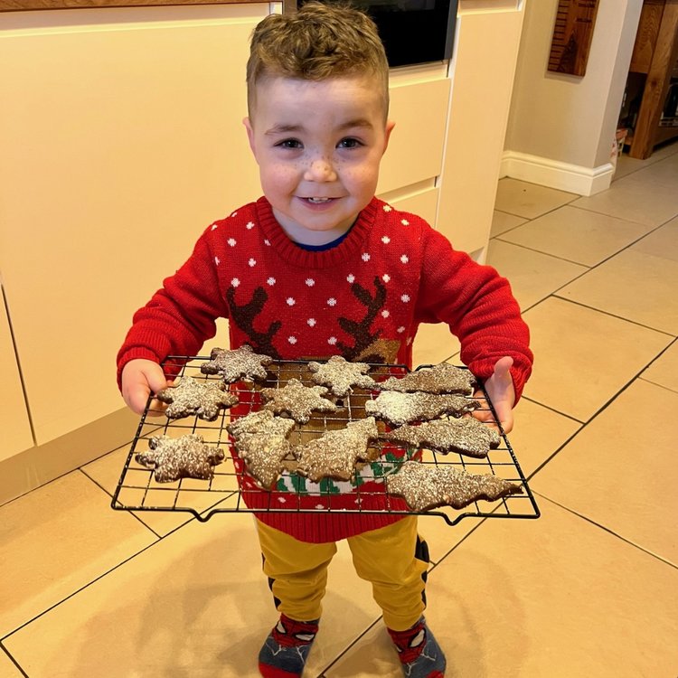 Daniel pictured at home, wearing a Christmas jumper and holding homemade cookies.