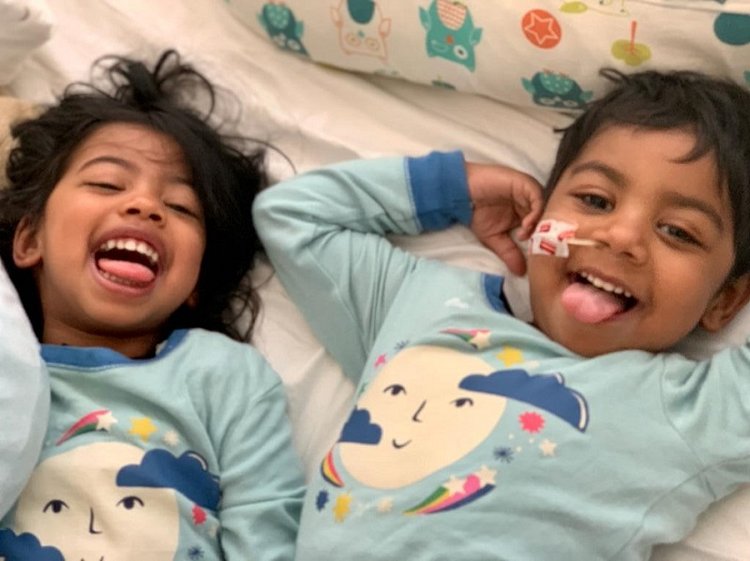 Two children lying down sticking their tongues out