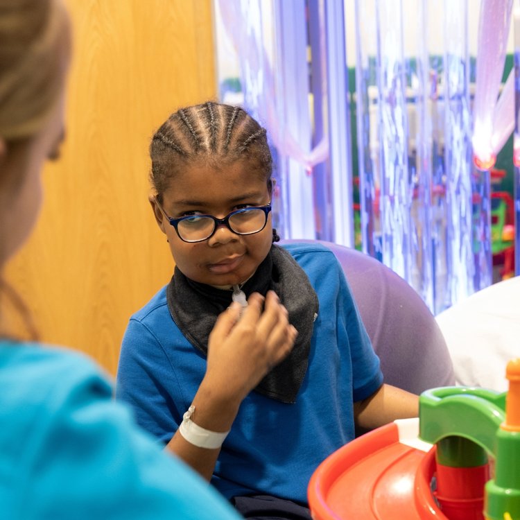 GOSH patient sitting in a chair in a playroom at GOSH