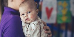 Baby in hospital room. She is looking to camera.