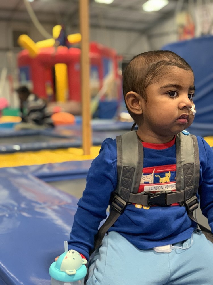 Little boy sitting by a soft play wearing a backpack