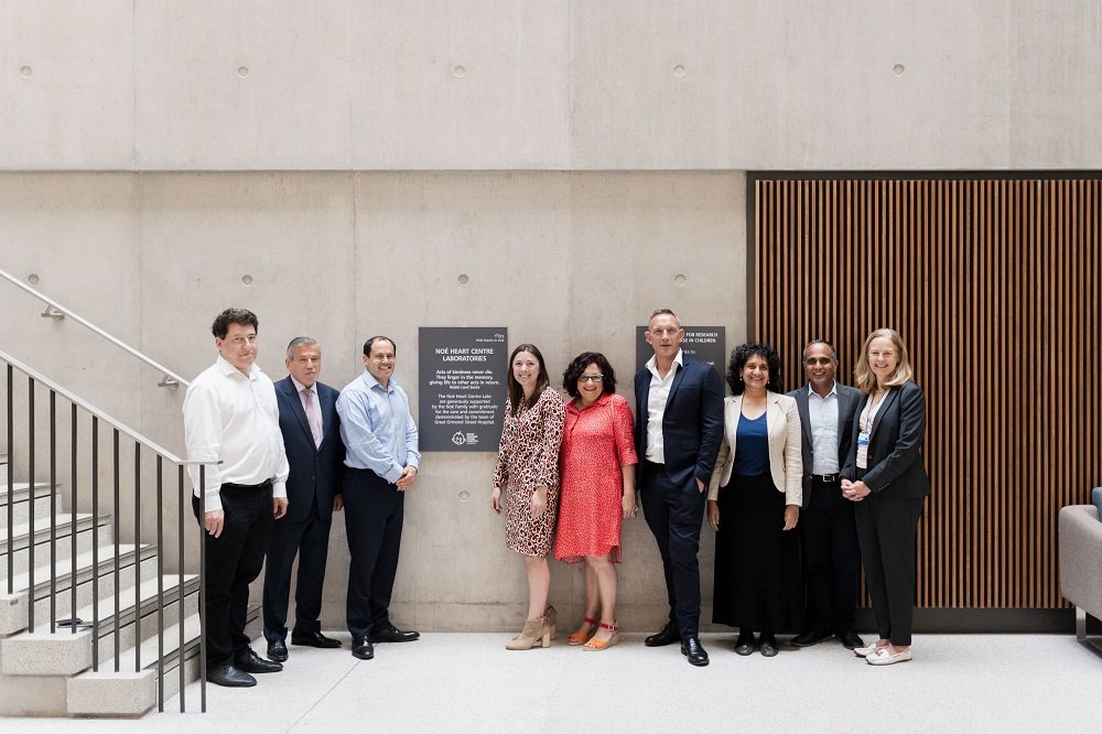 Nine men and women stand in front of a plaque to commemorate the Noe Heart Centre Labs