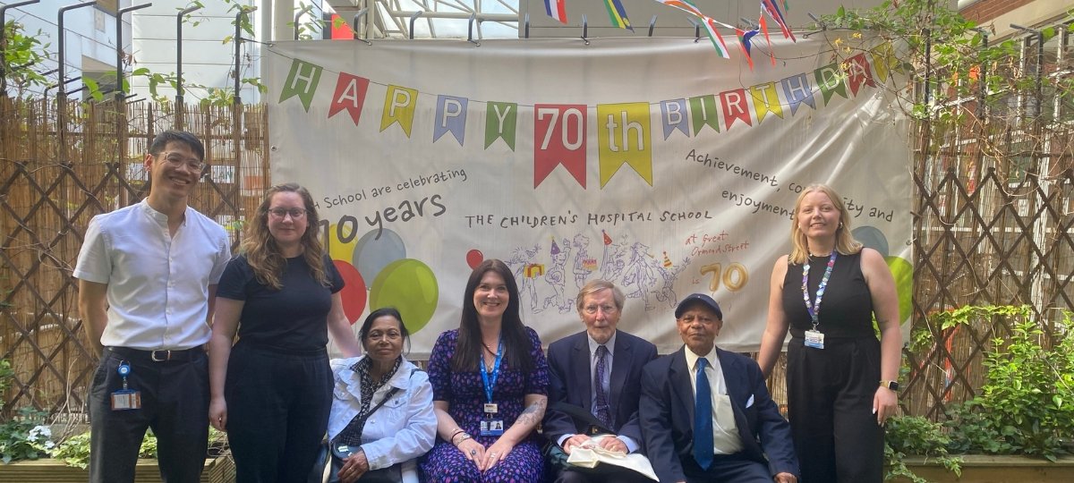 A group of people gather outside in front of a sign reading happy birthday to theGOSH School