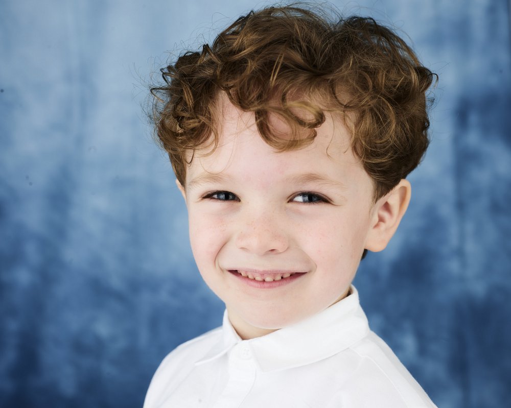 Portrait of GOSH patient Arthur by photographer Rankin. Arthur is wearing a white shirt and is smiling widely.