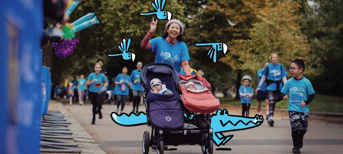 Race for the Kids participant smiles and waves to camera while pushing two babies in pushchair.