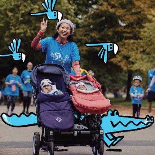 Race for the Kids participant smiles and waves to camera while pushing two babies in pushchair.