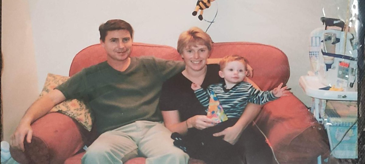 Baby Rhys sits next to his parents on a sofa on his birthday