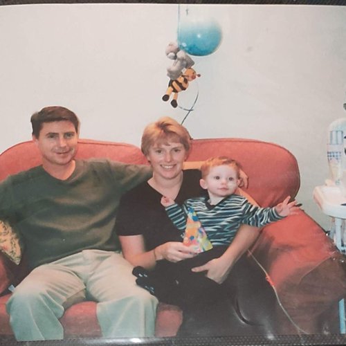 Baby Rhys sits next to his parents on a sofa on his birthday