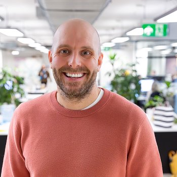 The CTO of GOSH Charity in the office smiling and looking into the camera