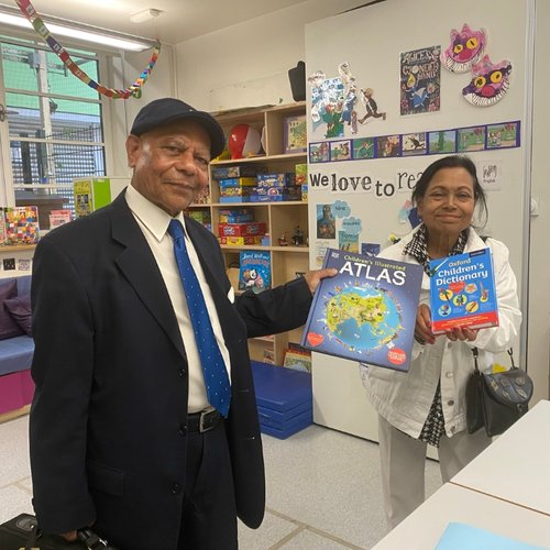A man and a woman stand in a classroom holding children's books