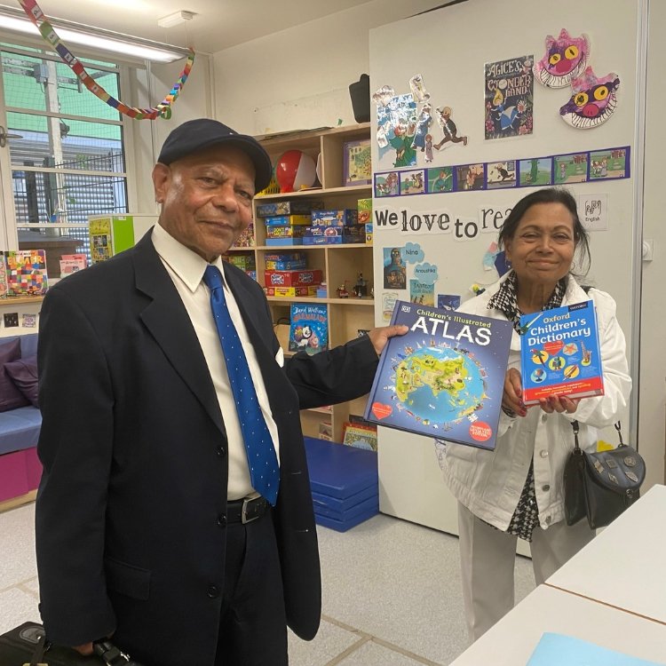 A man and a woman stand in a classroom holding children's books