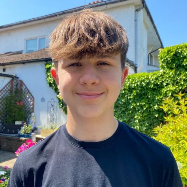 Close-up photo of Rowan today. He is standing outside, smiling and looking to-camera.