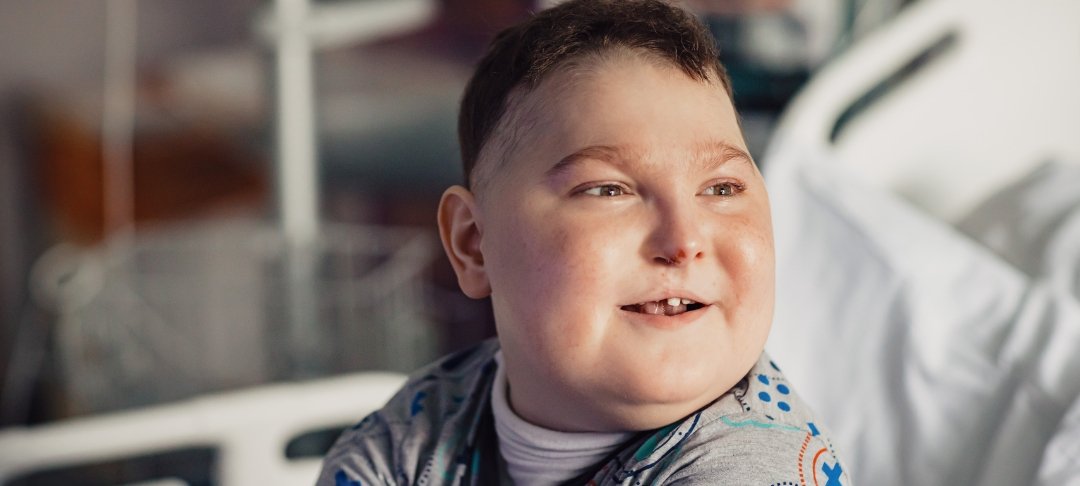 Headshot of boy sitting on bed at GOSH and smiling