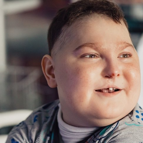 Headshot of boy sitting on bed at GOSH and smiling