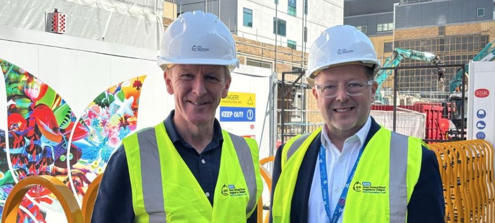 Tim posing with Jason (from Trust Board) outside the CCC construction site in a hi-vis jacket and safety hat