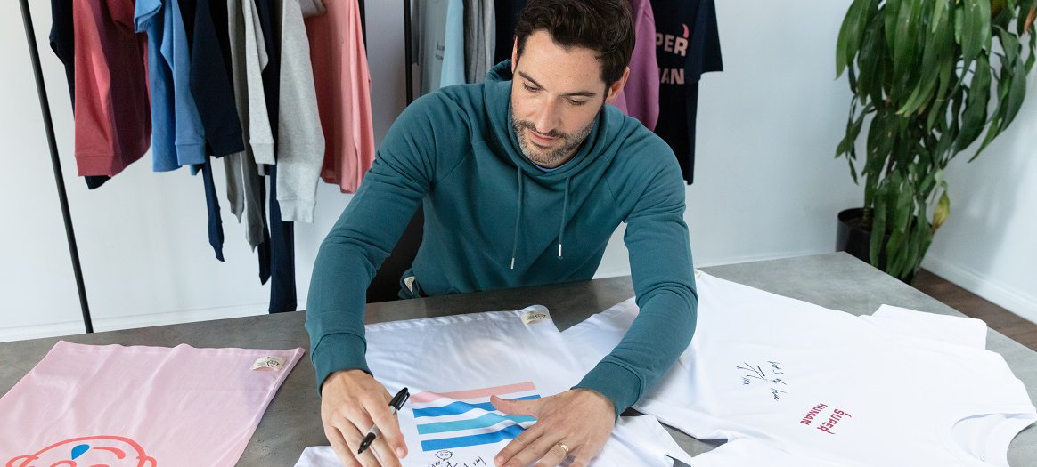 Tom Ellis signs a selection of clothes from the Rupert and Buckley collection