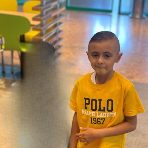 Little boy standing in a room at GOSH, smiling slightly and looking away from the camera