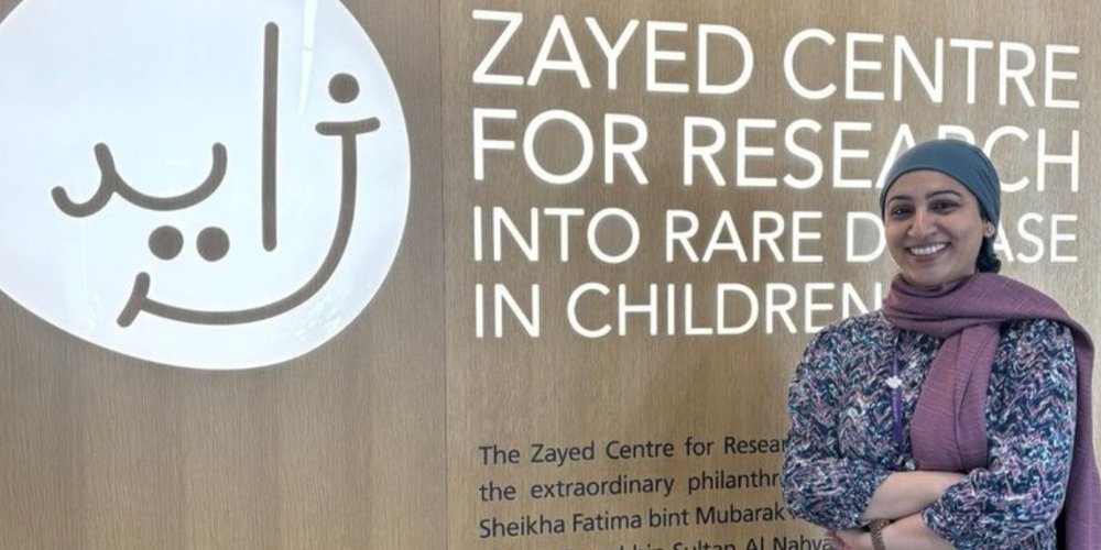 Dr Asma Naseem in front of entrance sign to the Zayed Centre for Research into Rare Disease in Children.