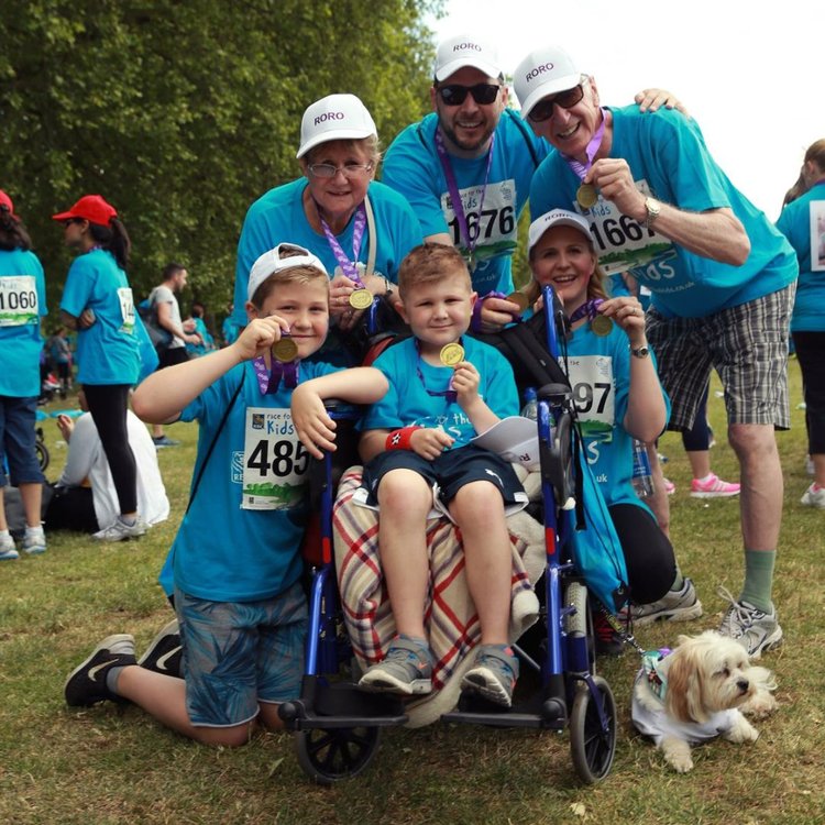 A younger Rowan pictured sitting in a wheelchair, surrounded by his family, at RBC Race for the Kids