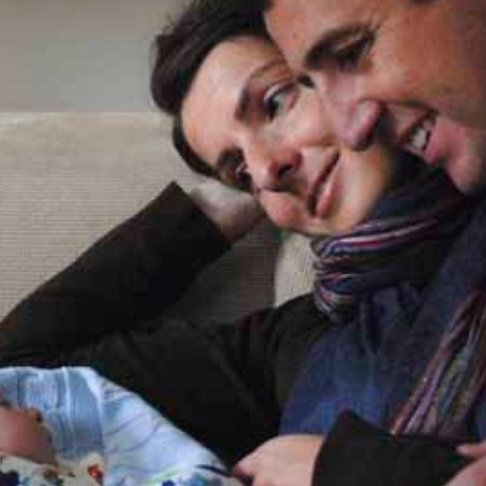 A man and woman hold and smile at their baby boy
