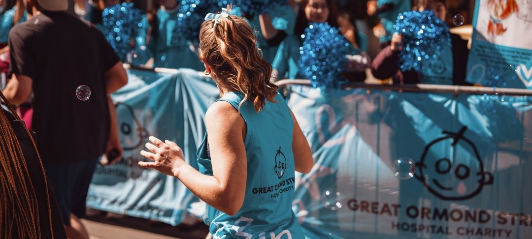 Woman running the London Landmarks Half Marathon for GOSH Charity runs past GOSH Charity cheer point