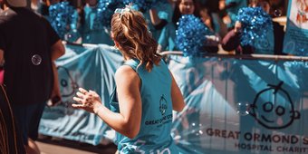 Woman running the London Landmarks Half Marathon for GOSH Charity runs past GOSH Charity cheer point