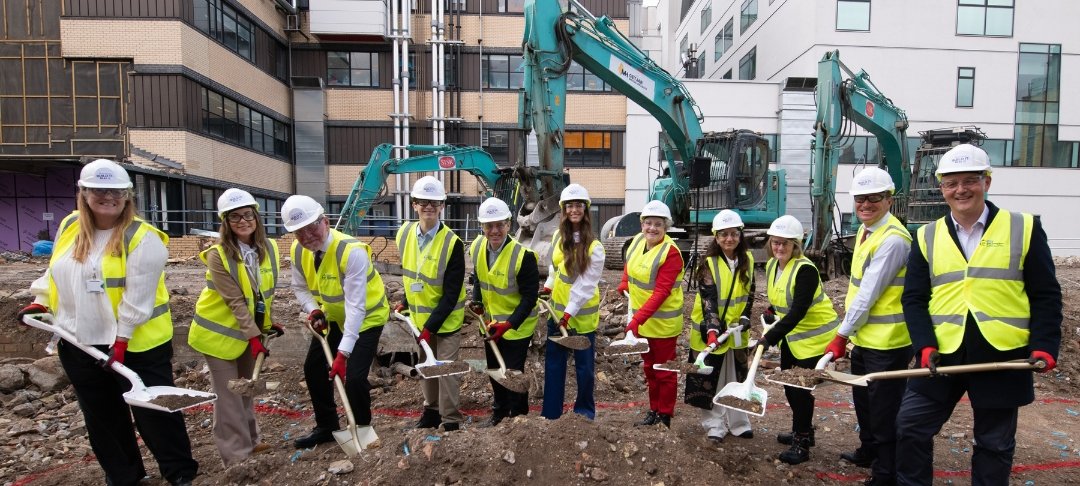 Group of people in high-vis jackets pretending to dig