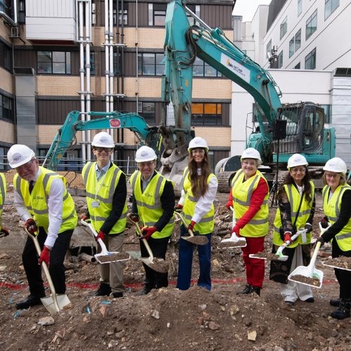 Group of people in high-vis jackets pretending to dig