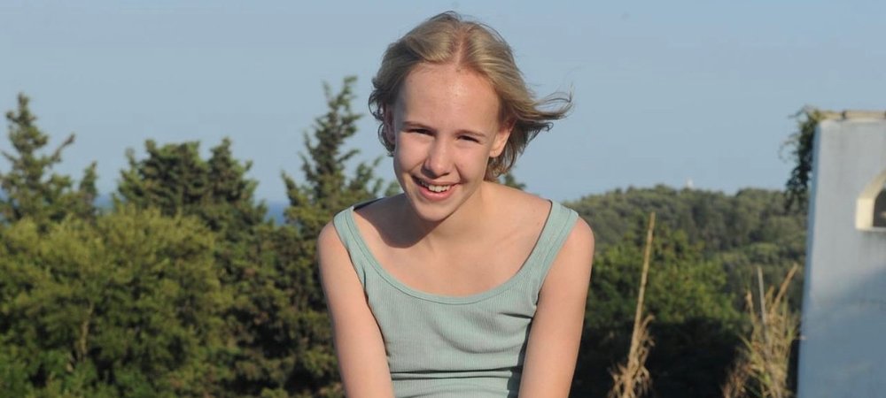 Teenage girl sitting outside in the sun, smiling