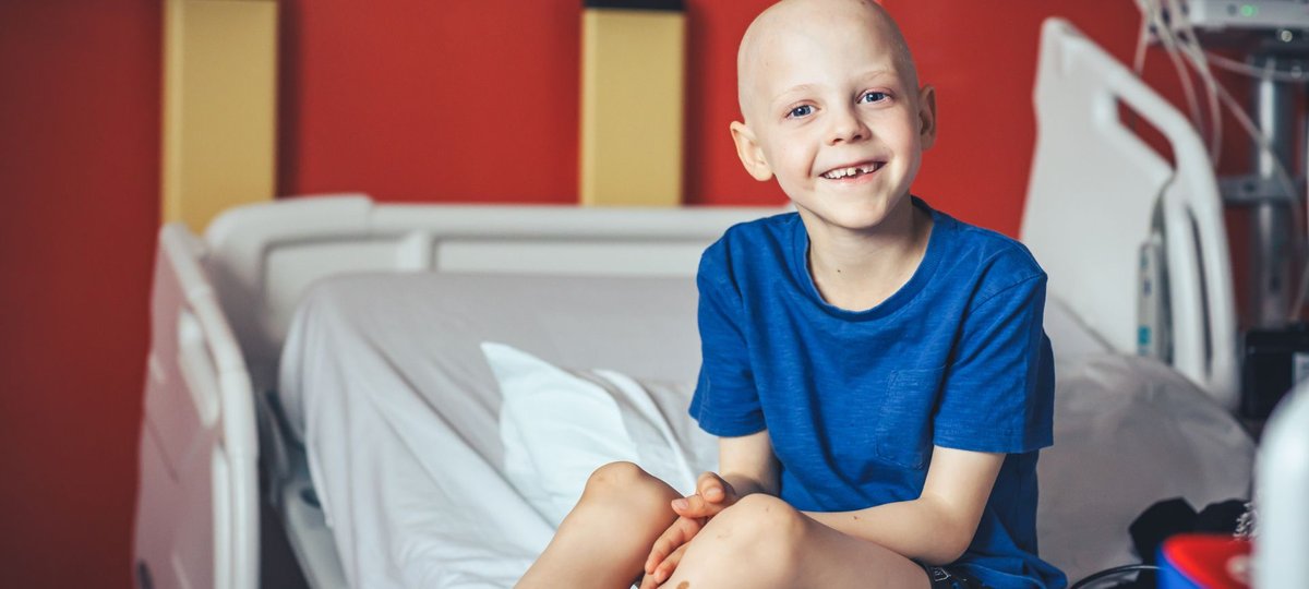 Little boy sitting on hospital bed, smiling to camera