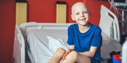 Little boy sitting on hospital bed, smiling to camera