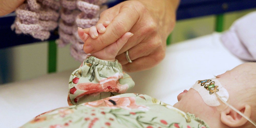 Volunteer and GOSH baby hold hands