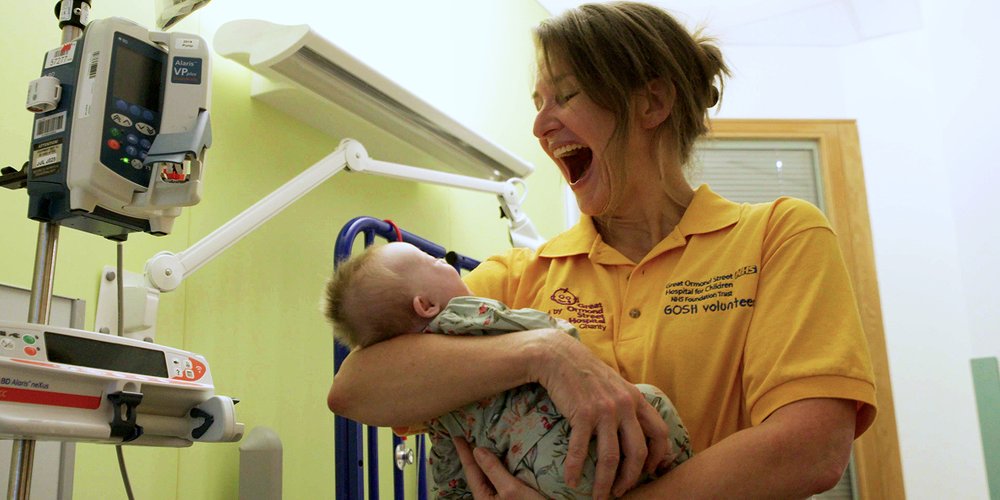 Volunteer holding baby with a wide smile